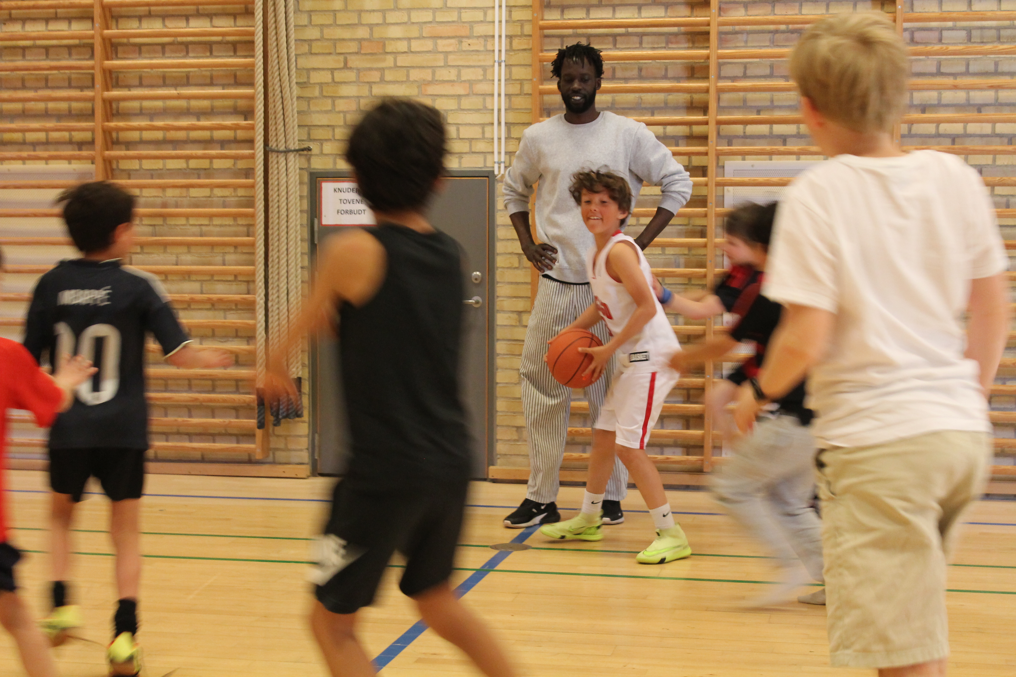 Coach Deng watching a young player handle the ball while teammates run past