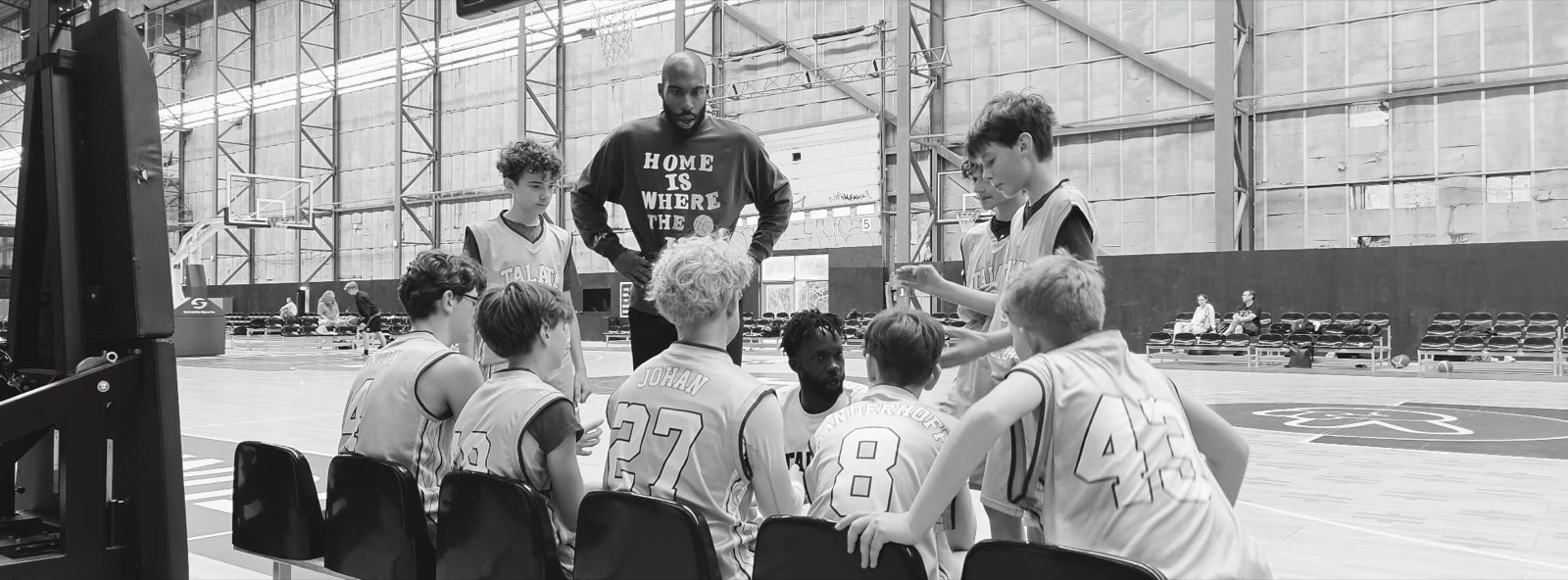 Coach and players in the huddle, black and white