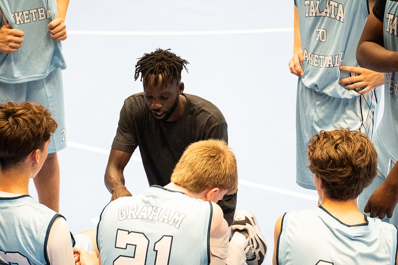 Coach Deng Awak talking to the squad in a huddle, seen from above