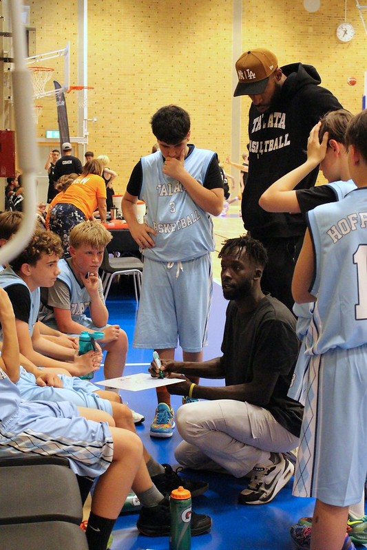 Coach Deng Awak and Jordan Naughton in a timeout with the squad
