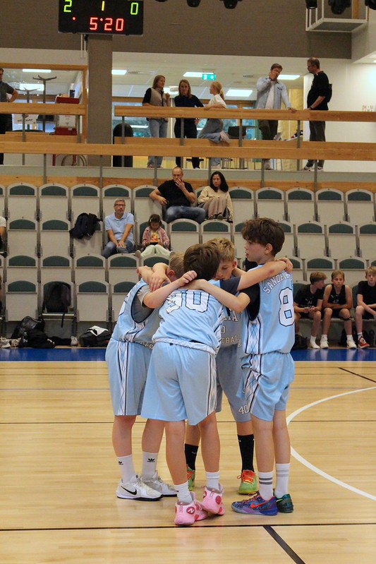 A Talata huddle on court with parents watching from the balcony