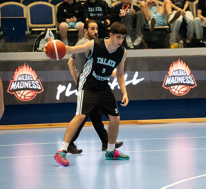 A Talata player with the ball in front of the Malbas Madness boards