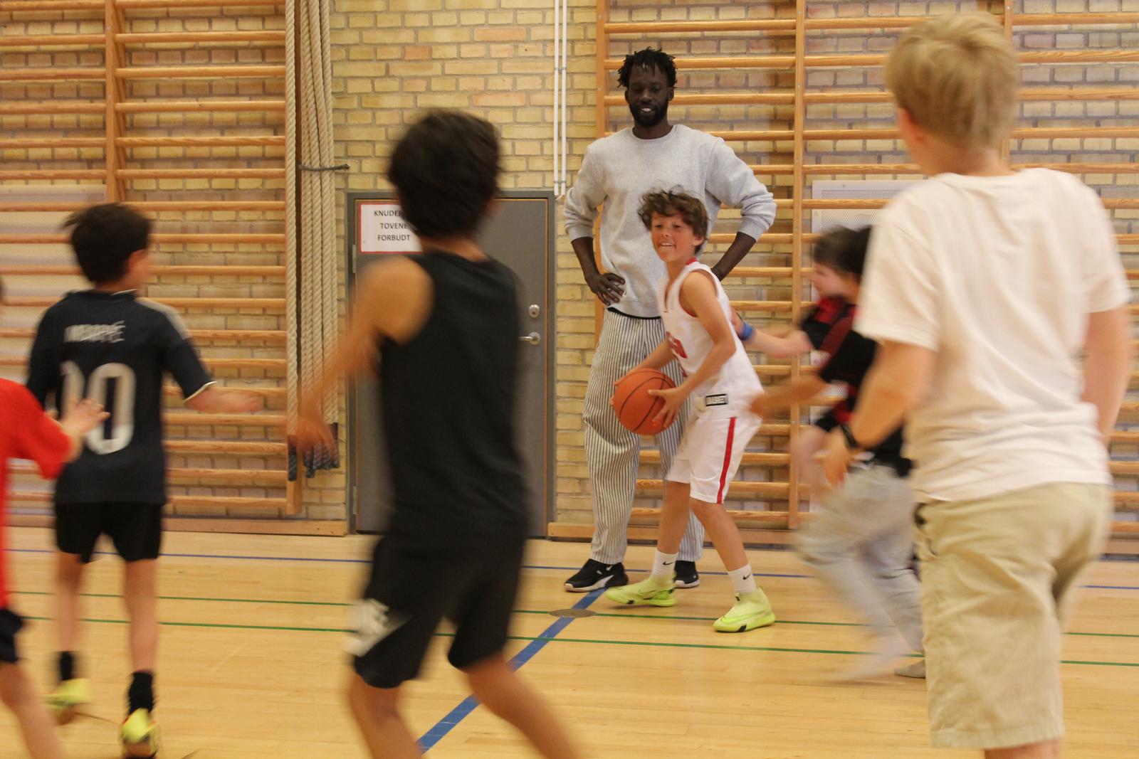 Coach Deng watching a young player handle the ball while teammates run past